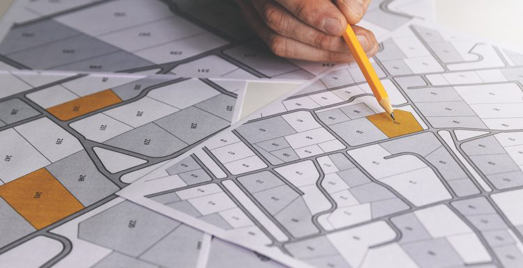 Hand holding pencil over site location map